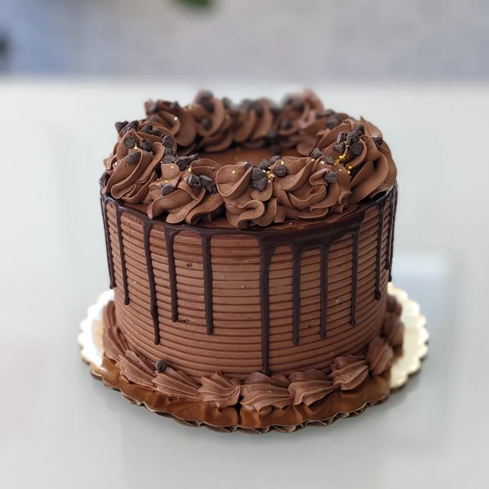 Chocolate buttercream cake with a chocolate drip and piped rosettes