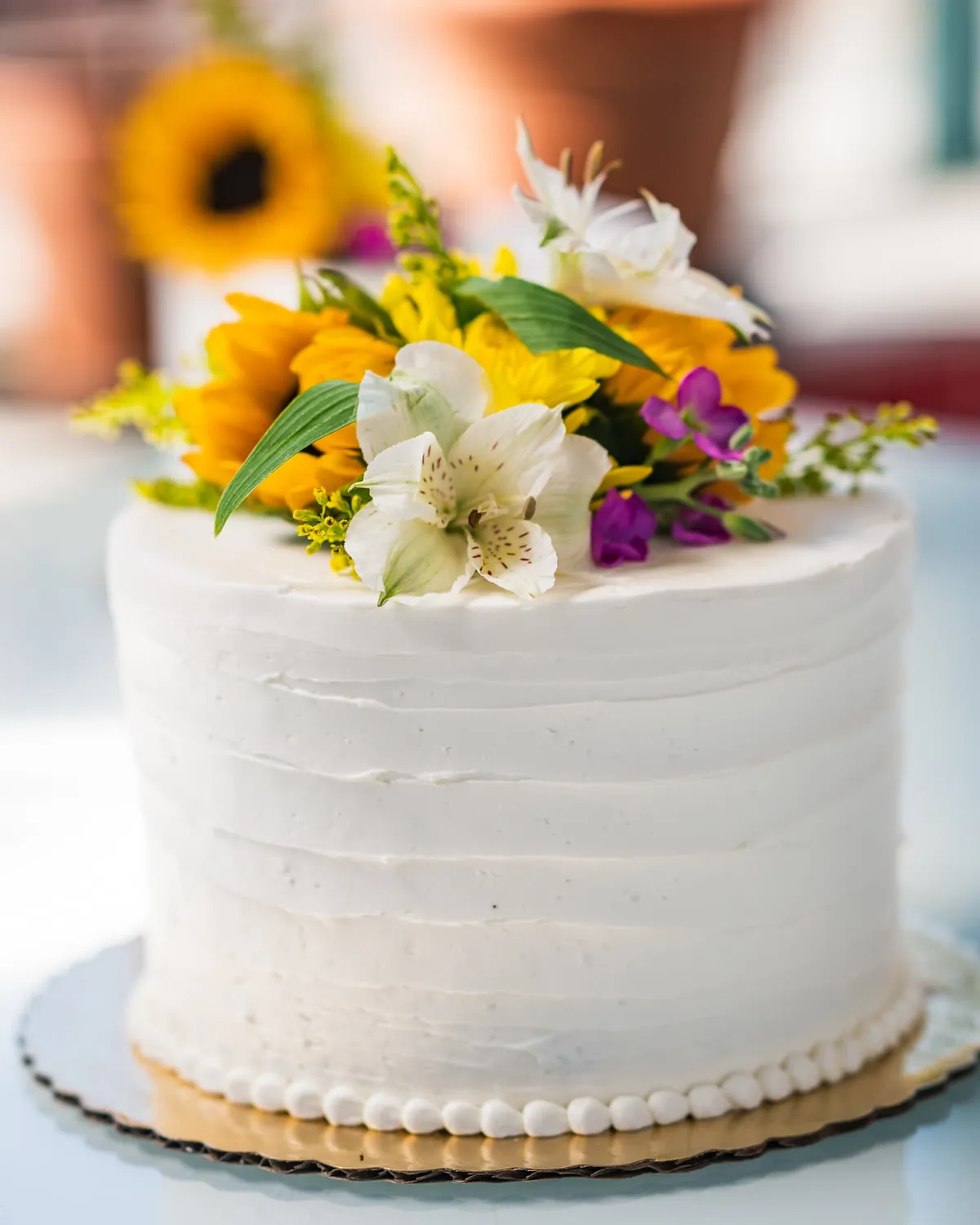 White rough-frosted cake topped with sunflowers