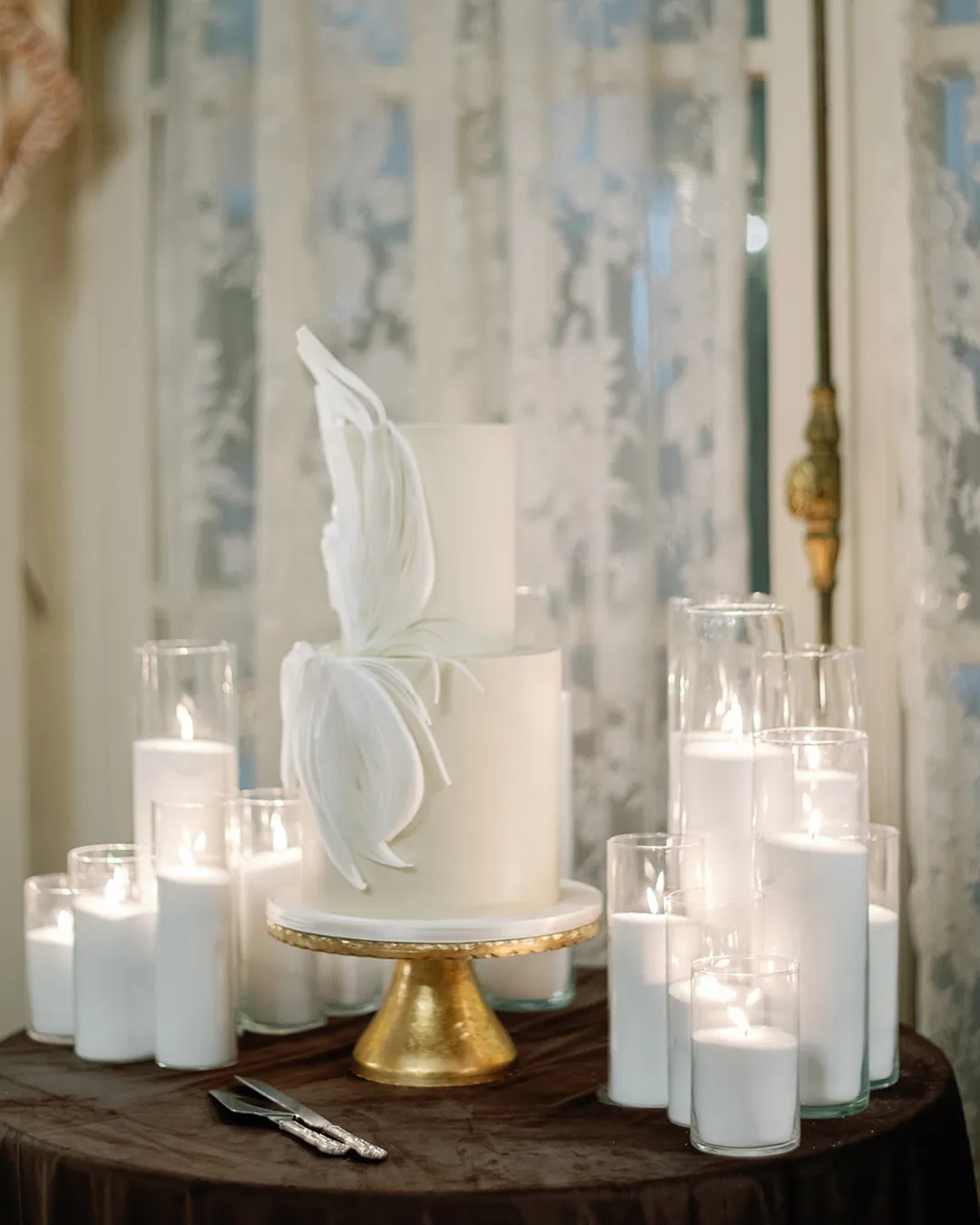 White wedding cake with a wafer-paper sculpture among candles